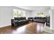 Bright living area with hardwood floors, two black leather couches, and large windows providing ample natural light at 3975 Denwood Dr, Indianapolis, IN 46226