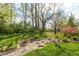 Serene backyard garden with stone walkway, mature trees, lush greenery, and decorative seating at 4281 Cairo Way, Avon, IN 46123