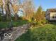 Landscaped backyard featuring a stone walkway, mature trees, and lush green lawn at 4281 Cairo Way, Avon, IN 46123