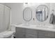 Modern bathroom featuring double sinks, vanity with gray cabinets, framed mirrors, and tiled shower-tub combo at 4615 Copper Grove Dr, Indianapolis, IN 46237