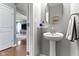 Charming powder room featuring pedestal sink, round mirror, and neutral tones at 5593 Ralfe Rd, Indianapolis, IN 46234