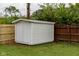 Close-up of a white storage shed in the backyard, next to a wooden fence at 5605 Glencoe St, Indianapolis, IN 46226