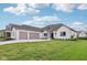 Beautiful white brick home with a three-car garage, green grass and professional landscaping at 5667 Skylark Dr, Greenwood, IN 46143