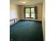 Bedroom with plush green carpet, neutral walls, and a window with peaceful view at 636 Mallards Xing # 2-A, Martinsville, IN 46151