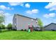 A view of the backyard featuring lush green grass, play set, and a gray sided home with a chimney at 6624 Lakestone Ct, Indianapolis, IN 46237