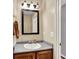 Bathroom with a wooden vanity, white sink, framed mirror, and neutral colored walls at 6624 Lakestone Ct, Indianapolis, IN 46237