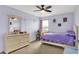 A charming bedroom with a ceiling fan, dresser, and bed with purple bedding at 6624 Lakestone Ct, Indianapolis, IN 46237