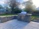 Outdoor kitchen with built in grill and stone surround on a patio and manicured lawn at 6625 Wolverine Way, Indianapolis, IN 46237