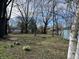 A serene backyard with a mix of large trees, seasonal flowers, and blue house at 7131 E 14Th St, Indianapolis, IN 46219