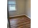 Bedroom showing wood-look floors, a window letting in natural light, and neutral walls at 7131 E 14Th St, Indianapolis, IN 46219
