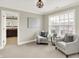 Neutral sitting room showcasing large window, adjacent bathroom, and two gray accent chairs at 7614 Bishops, Zionsville, IN 46077