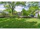 Expansive backyard featuring lush lawn, mature trees, gardens, and outdoor patio area at 7843 Windcombe Blvd, Indianapolis, IN 46240
