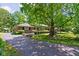 Brick home with a long driveway, mature trees, a manicured lawn, and trimmed shrubbery at 7843 Windcombe Blvd, Indianapolis, IN 46240