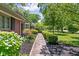 Stone walkway with manicured shrubbery leading to a red brick home, highlighted by green foliage at 7843 Windcombe Blvd, Indianapolis, IN 46240