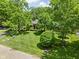 Landscaped front yard featuring a lush lawn, manicured shrubs, and mature trees at 7843 Windcombe Blvd, Indianapolis, IN 46240