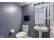 Modern half bathroom with blue walls, white fixtures, and a decorative mirror at 8316 Thorn Bend Dr, Indianapolis, IN 46278