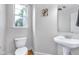 Powder room features a pedestal sink, white toilet, wood look flooring, and a decorative mirror at 952 Junction Pl, Indianapolis, IN 46220