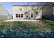 View of the home's backyard with a patio and a mix of grass and leaves in a partially snow covered yard at 9955 Orange Blossom Trl, Fishers, IN 46038