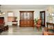 Cozy living room featuring wood-look floors, a large china cabinet, elegant chairs, and natural light from the window at 9955 Orange Blossom Trl, Fishers, IN 46038