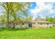 Expansive backyard featuring a stone home with a brick chimney and sliding glass doors at 10827 Wonderland Dr, Indianapolis, IN 46239