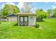 Backyard featuring a detached storage shed, lush grass, and mature trees at 10827 Wonderland Dr, Indianapolis, IN 46239