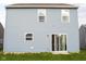 Back exterior view of a light blue home with a well-maintained lawn and sliding glass doors to the patio at 10835 Spirit Dr, Ingalls, IN 46048