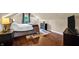 Cozy bedroom with hardwood floors, tufted headboard bed, natural light, mini split, and a dresser for storage at 1107 N Hartman Dr, Indianapolis, IN 46219