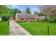 Charming brick home with red shutters, a well-manicured lawn, and a concrete walkway and drive at 1107 N Hartman Dr, Indianapolis, IN 46219
