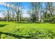 View of the level backyard with home in the distance, framed by mature trees at 11471 Clarkston Rd, Zionsville, IN 46077