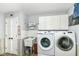 Well-organized laundry room featuring a utility sink, washer, dryer, white cabinets, and wood-look flooring at 11550 Clarkston Rd, Zionsville, IN 46077
