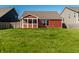 Expansive backyard featuring a lush lawn and a charming red home with a screened-in porch at 1221 Danielle Rd, Lebanon, IN 46052