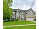 Charming two-story brick home with a green lawn, a two-car garage, and a beautifully landscaped front yard at 1454 Woodfield Dr, Greenwood, IN 46143