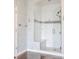 Modern glass shower with white tile, built-in seat, and rainfall showerhead in updated bathroom at 1510 Continental Dr, Zionsville, IN 46077