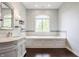 Bright bathroom features a soaking tub under a window, marble countertops, and a stylish vanity at 1510 Continental Dr, Zionsville, IN 46077