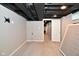 Unfinished basement space with neutral carpet, open ceiling, and tv mount at 1701 Lincoln Rd, Speedway, IN 46224