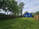 A spacious backyard with a blue house, wooden fence and mature trees at 2737 S Roena St, Indianapolis, IN 46241