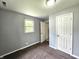A cozy bedroom featuring gray walls, brown carpet, a window, and a white door at 2737 S Roena St, Indianapolis, IN 46241