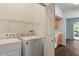 A bright and tidy laundry area featuring essential appliances and a storage shelf, ready for convenience at 4136 Orchard Valley Ln, Indianapolis, IN 46235