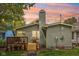 Charming backyard featuring a cozy deck, string lights, beautiful landscaping, and a traditional brick chimney at 4245 Guilford Ave, Indianapolis, IN 46205