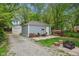 Detached garage with a gravel driveway, patio, woodpile, and outdoor seating area, surrounded by mature trees at 4245 Guilford Ave, Indianapolis, IN 46205