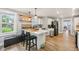 Open kitchen with island, white cabinets, floating shelves, stainless appliances, and stylish pendant lights at 4245 Guilford Ave, Indianapolis, IN 46205