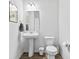 Bright, white powder room features pedestal sink, wood-look flooring, and modern fixtures at 4629 Rainwater Ln, Whitestown, IN 46075