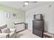 A bedroom with light green walls, animal artwork, dresser with changing station, and comfortable chair at 4629 Rainwater Ln, Whitestown, IN 46075