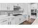 White cabinets, gray backsplash and stainless hood over gas cooktop are kitchen highlights at 4629 Rainwater Ln, Whitestown, IN 46075