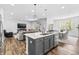 Open-concept kitchen with gray island, stainless appliances, and modern pendant lighting with views of living room at 4629 Rainwater Ln, Whitestown, IN 46075