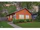 Charming orange single-story home featuring a well-manicured lawn and a vibrant blue door at 4810 Winthrop Ave, Indianapolis, IN 46205