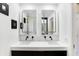 Modern bathroom featuring double sinks, sleek black fixtures, and illuminated rectangular mirrors at 51 Wilson Dr, Carmel, IN 46032