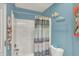 Bathroom featuring a bathtub with shower, white toilet, blue walls, and decorative artwork at 5348 Pelham Way, Indianapolis, IN 46216