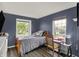 Cozy bedroom with wood floors and two bright windows, desk, chair, and stylish blue walls at 5348 Pelham Way, Indianapolis, IN 46216