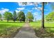 A serene park featuring lush green grass, mature trees, and a paved walking path at 5348 Pelham Way, Indianapolis, IN 46216